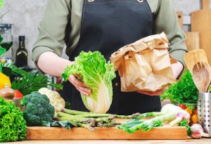 Mulher tirando as verduras da sacola de mercado