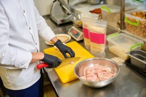 Cozinheira cortando pedaços de frango